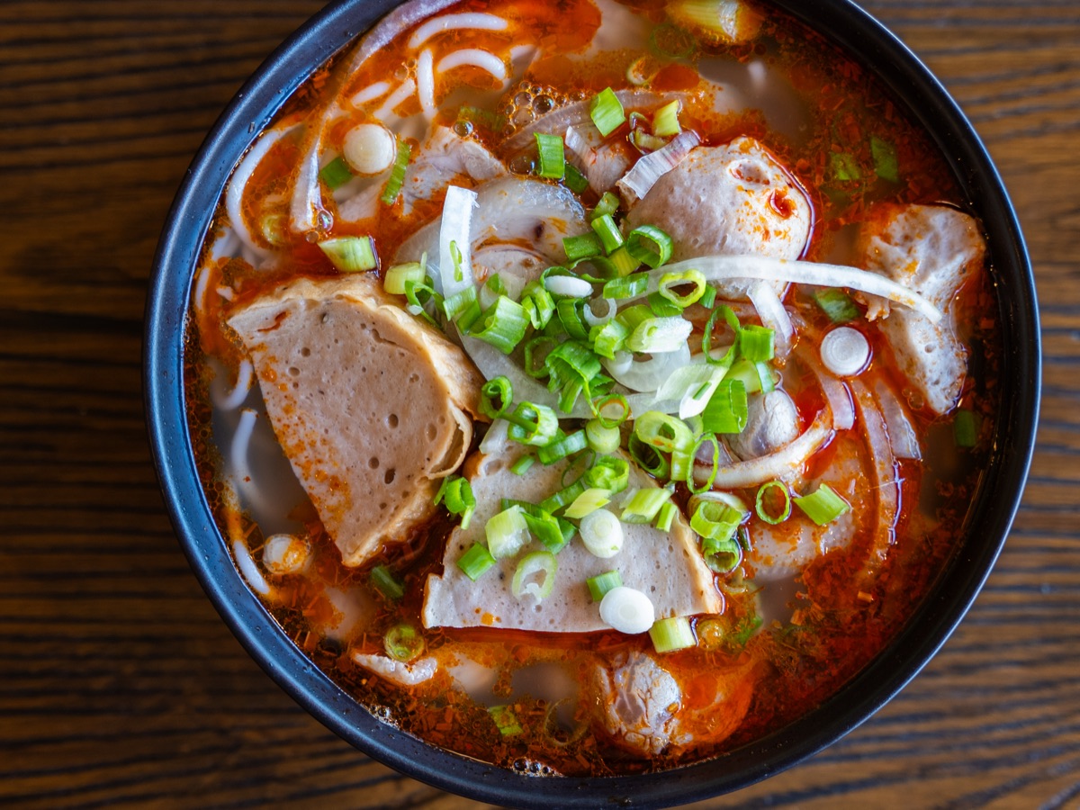 Bún bò Huế — spicy lemongrass beef noodle soup with pork meatloaf and scallions